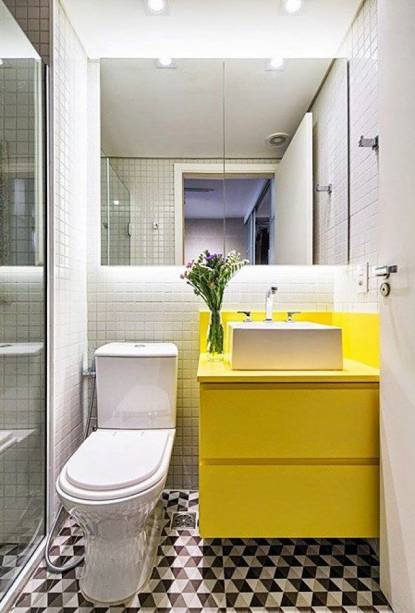 O piso com padrão geométrico, a marcenaria em amarelo e a iluminação são os responsáveis pelo charme deste minibanheiro com décor moderno.