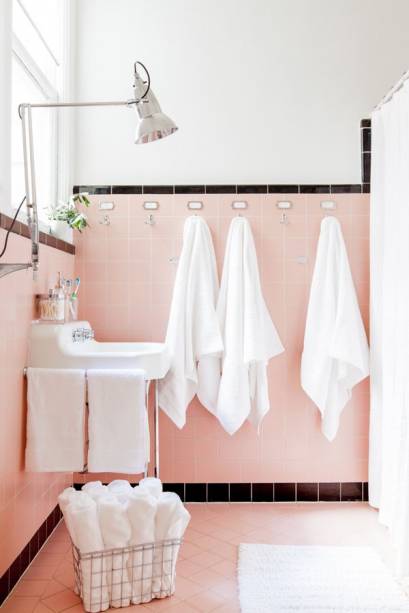 Para destacar o piso e os azulejos cor de rosa originais - com rodapé e uma borda em preto - o banheiro recebeu uma mão de tinta branca nas paredes e iluminação nova.