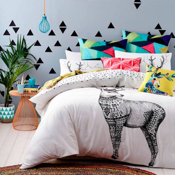 A decoração moderna, onde predominam os tons de azul, foi enriquecida com a trama colorida do tapete e o detalhamento das estampas.