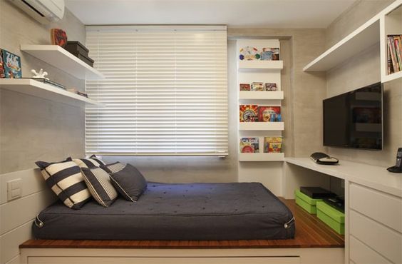 Neste quarto pequeno, a cama fica em uma plataforma. Várias prateleiras e caixas organizadoras dão conta de organizar livros e armazenar o que for necessário.