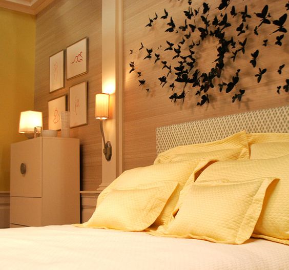O amarelo da roupa de cama conversa com a madeira do painél, dando todo o destaque para as borboletas penduradas sobre a cama.
