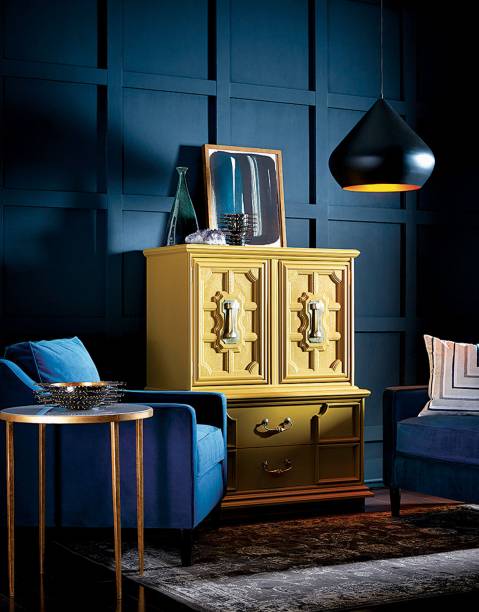 Neste hall, o armário amarelo contrasta com as paredes pintadas em um azul escuro, SW 9179 Anchors Aweigh, da Sherwin-Williams.