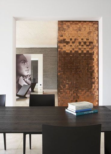 Esta parede de cobre, dividindo ambientes, torna a décor ainda mais elegante.