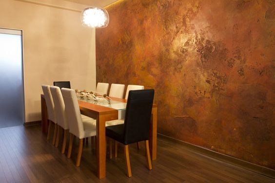 Olha como esta sala de jantar ficou extremamente elegante com a parede de cobre e as cadeiras neutras.