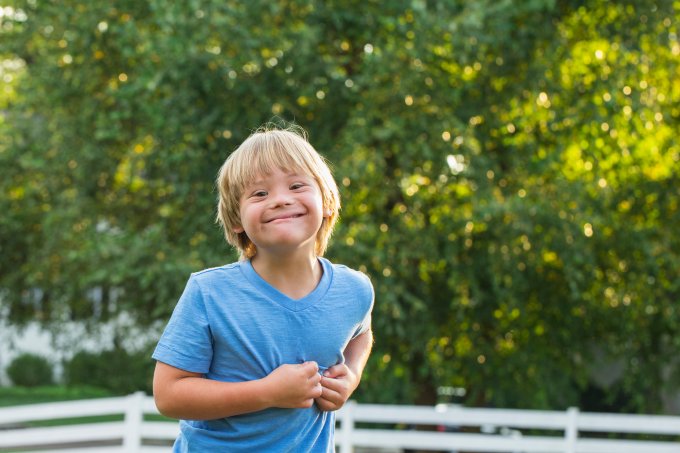 Caucasian boy with Down Syndrome smiling outdoors