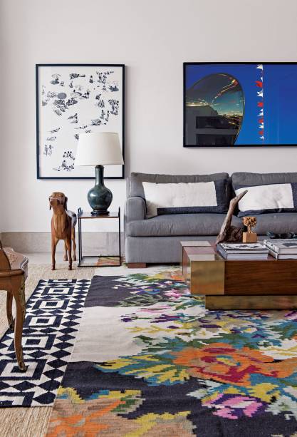 Sala com trâs tapetes sobrepostos: de juta, kilim geométrico e kilim floral, em projeto da moradora, a designer Maria Di Pace.