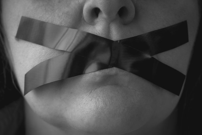Portrait of a woman with an x of adhesive tape covering her mouth