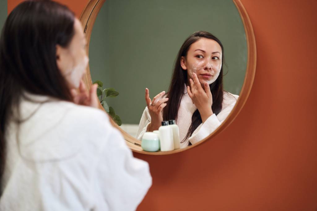 Asian woman applying moisture cream at her face Pele