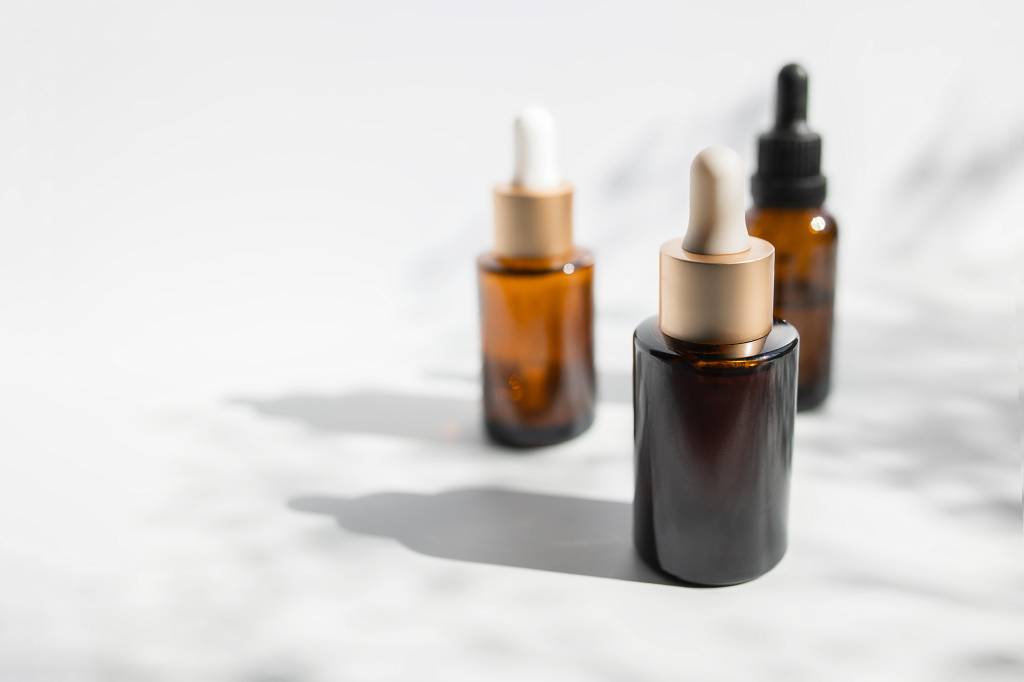 Brown glass with a dropper. Bottle mockup cosmetic oil dropper on a grey background and shadows. Copy space óleos capilares em base de marmore