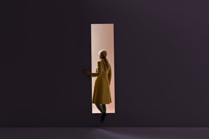 Woman walking into rectangular opening in coloured wall