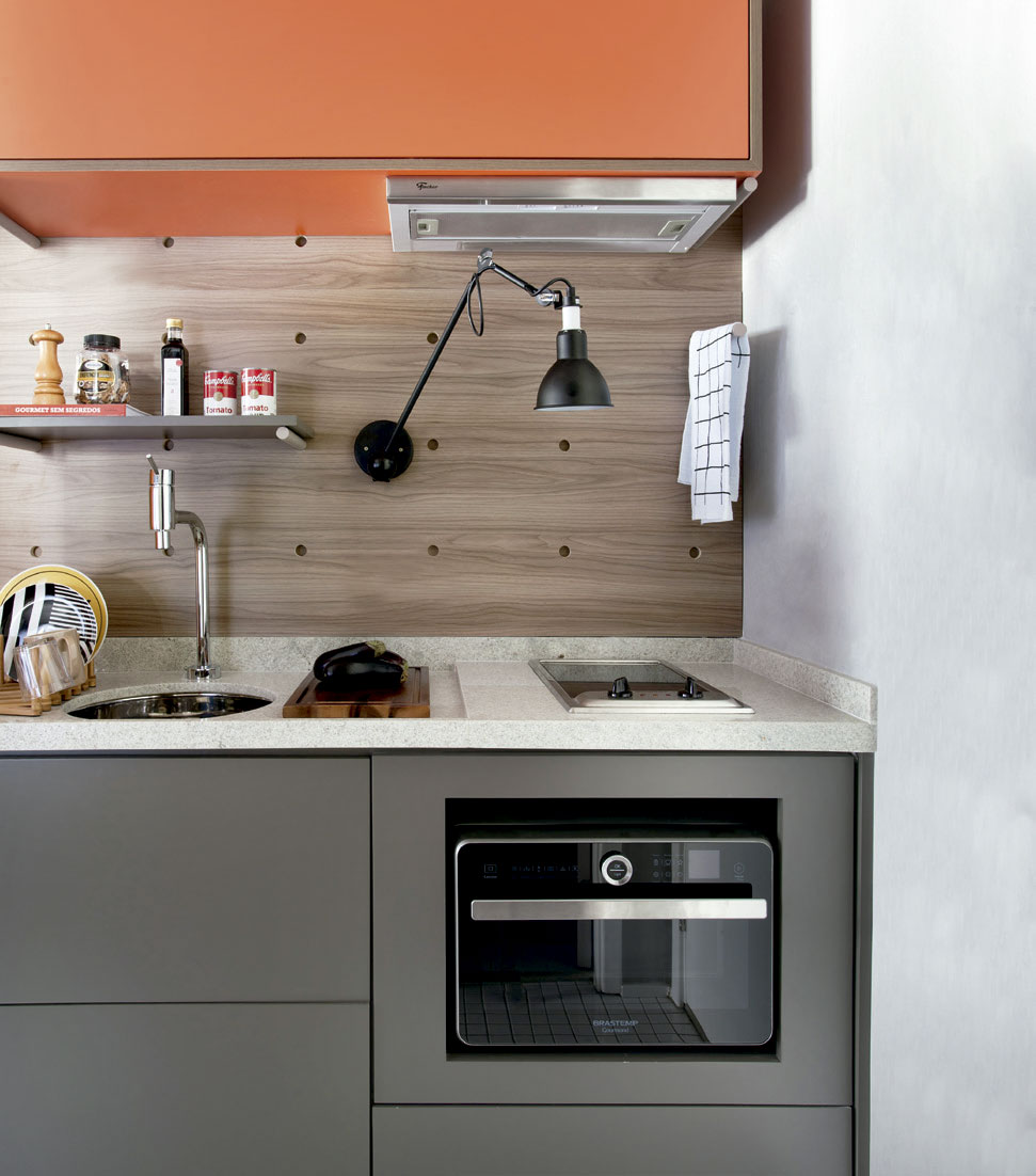 Com décor colorido e pegada industrial, este apartamento inteiro é menor do que o living de muita gente. Furos no painel (Marcenaria Santíssima Fé) deixam trocar nichos e prateleiras de lugar.