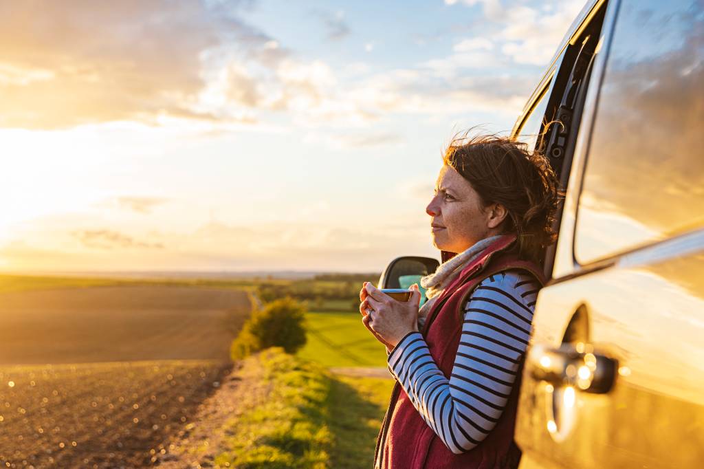 Woman looking at the view from her campervan mulher viajando de carro
