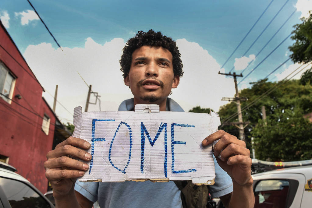 Homem segura pequeno cartaz com a mensagem: "FOME".