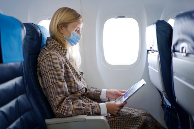 Mulher usa máscara facial num avião.