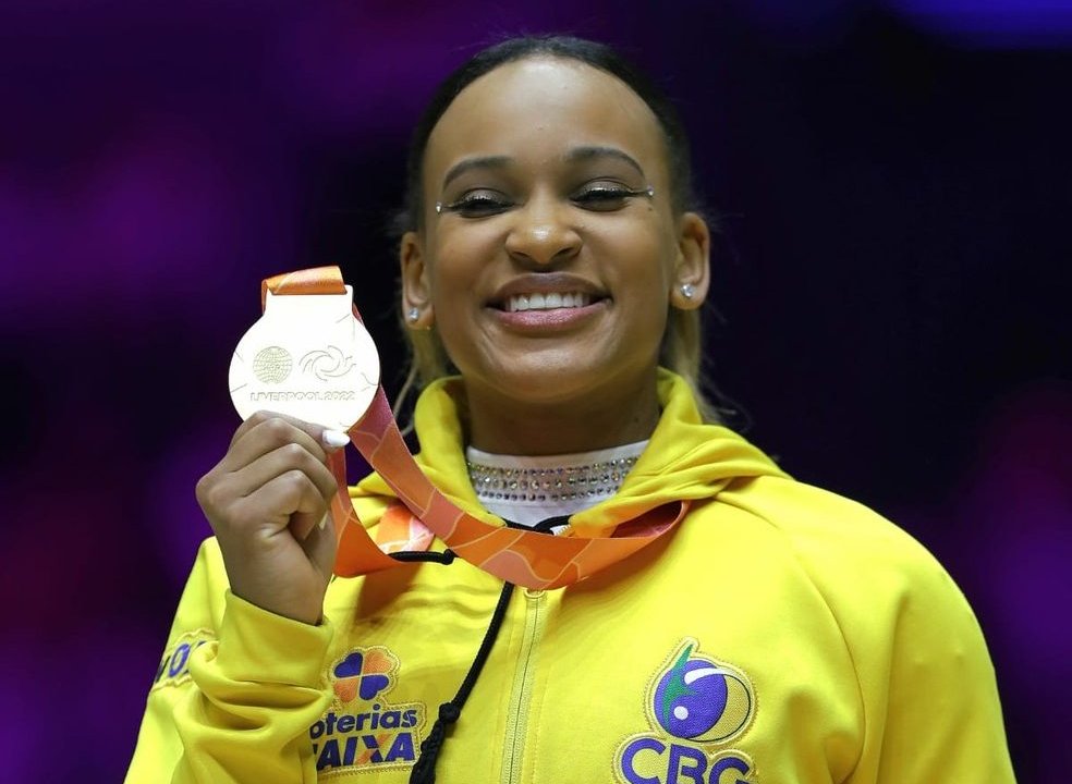 Rebeca Andrade posa sorridente com sua medalha de ouro no individual geral do Mundial 2022.