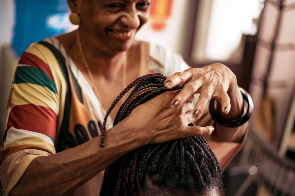 Maria das Graças sorri, enquanto atende uma de suas clientes no Afro N'zinga.