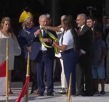 Momento em que Aline Souza entrega a faixa presidencial para Luiz Inácio Lula da Silva.