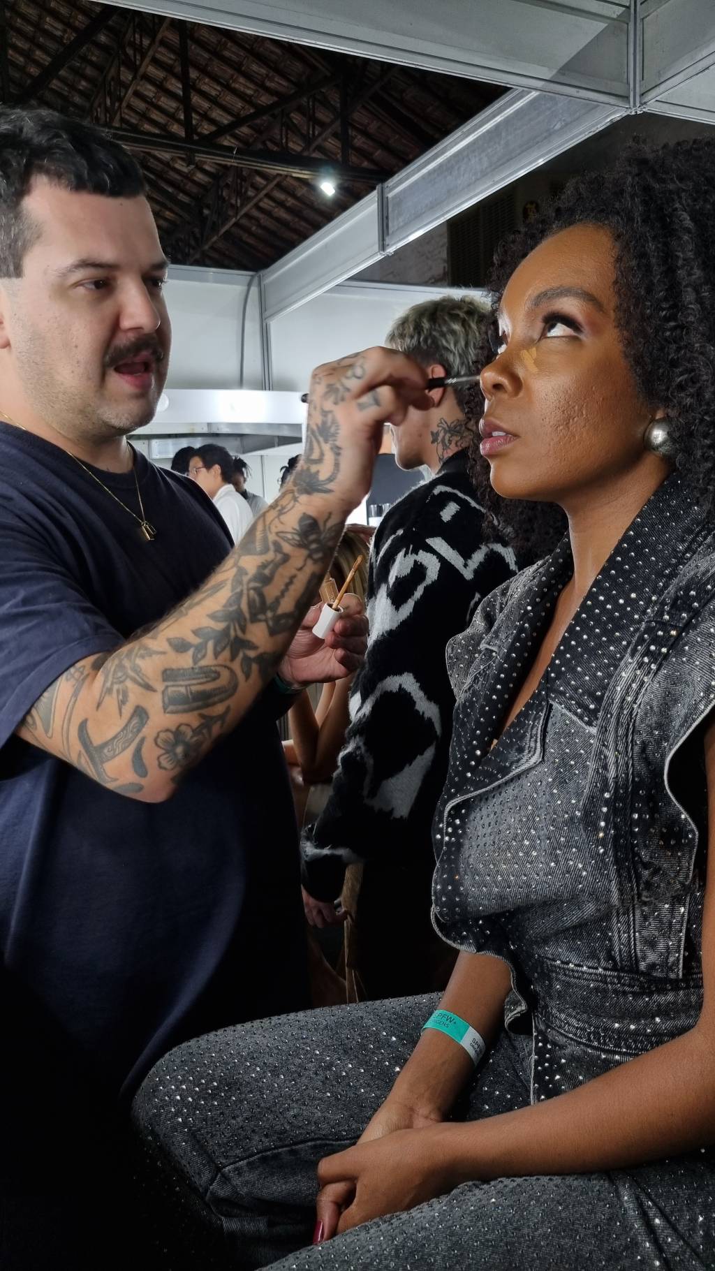 20230526_194347 (1) Helder Rodrigues dando um freshen up no make de Thelma Assis antes do desfile da LED