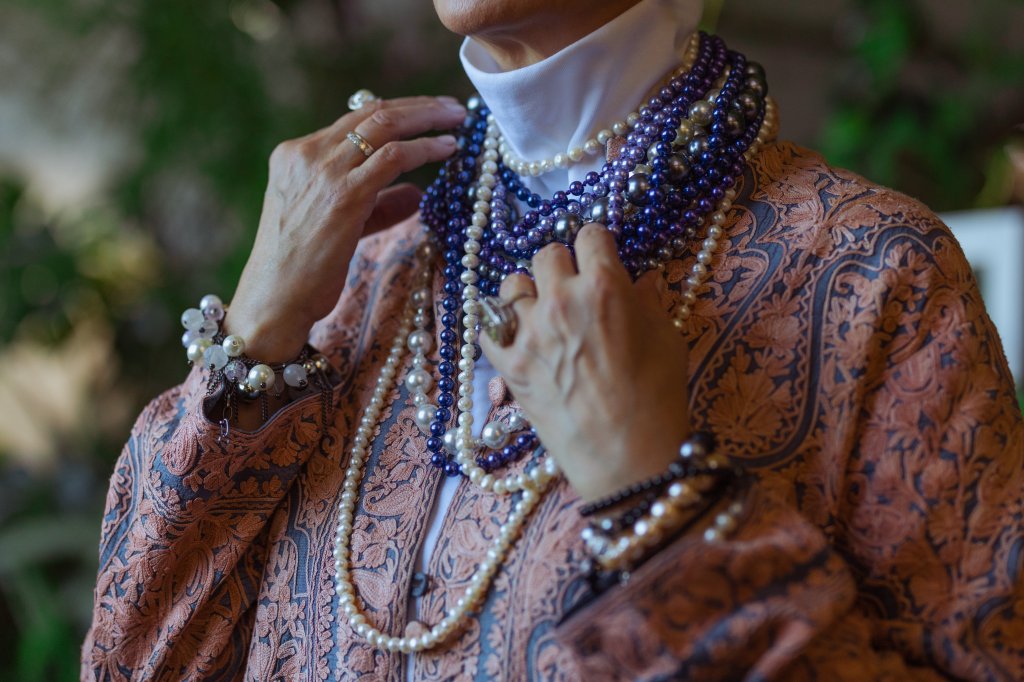 Mulher com diversos colares de pérolas em tons de azul e branco