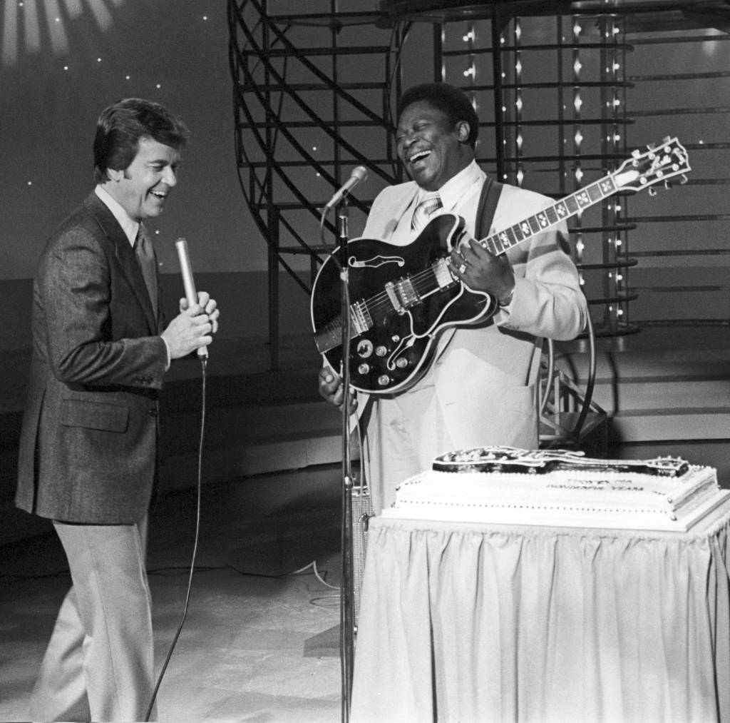 B.B. King é surpreendido com um bolo de aniversário no programa de televisão American Bandstand, em 1979. Ao seu lado, está o apresentador Dick Clark