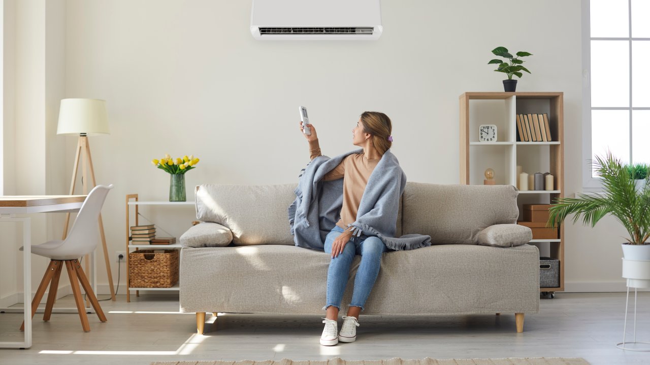 Mulher desfrutando ar fresco fresco fresco em sua sala de estar com ar condicionado na parede