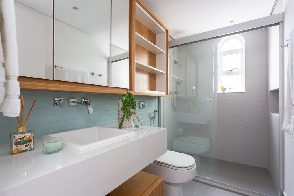 Banheiro vintage com revestimento em tons de azul e armários amadeirados com espelho