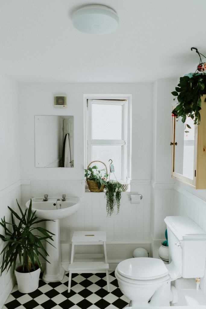 Banheiro vintage/retrô com piso quadriculado e louças mais clean, em tons de branco e off-white