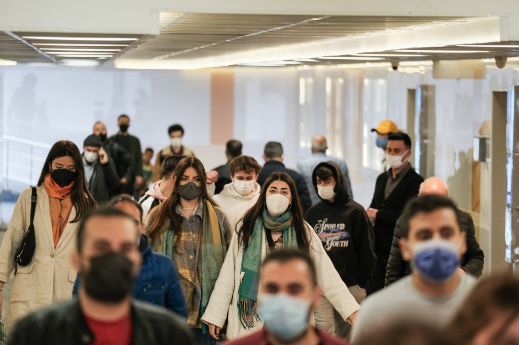 Aeroporto onde pessoas estão circulando com máscaras