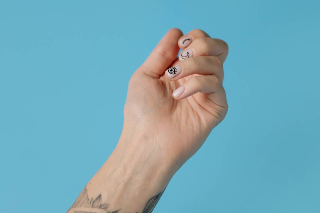 crescimento-saudável-unhas-fortalecimento Mão com unha decorada no fundo azul
