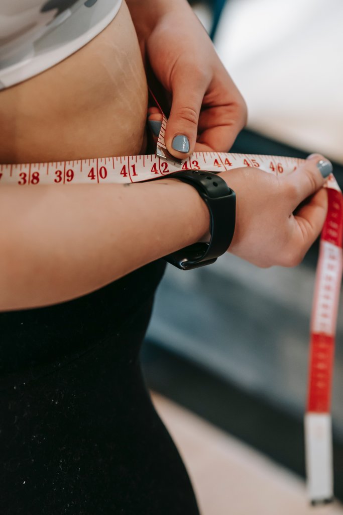 Mulher medindo sua cintura com uma fita métrica