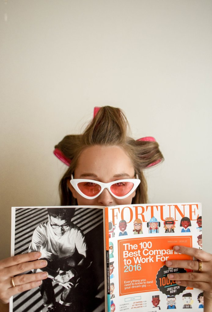 Mulher lendo uma revista enquanto usa bobes no cabelo
