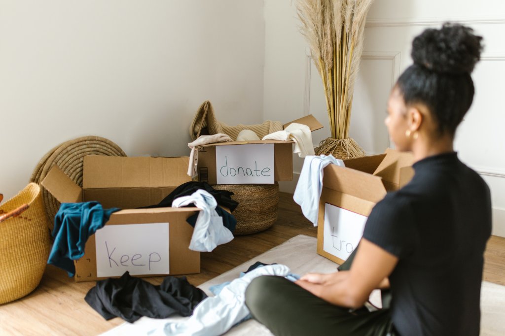 Mulher separando roupas para doação em caixas de papelão
