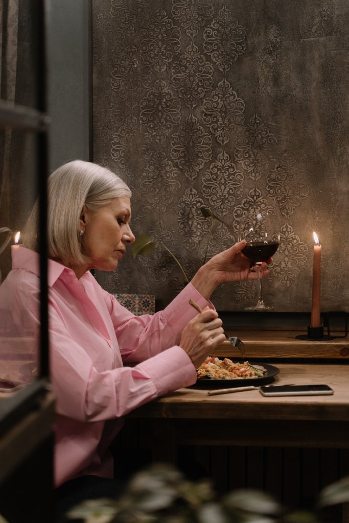 Mulher jantando com uma taça de vinho