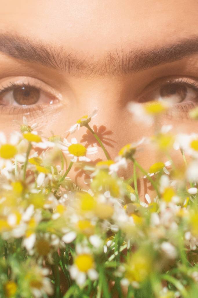 Mulher com monocelha cobrindo o rosto com flores