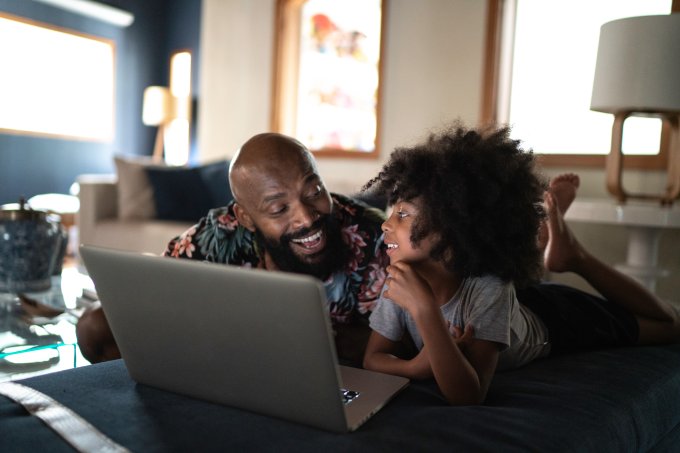Single father wacthing movie on a laptop with his daughter