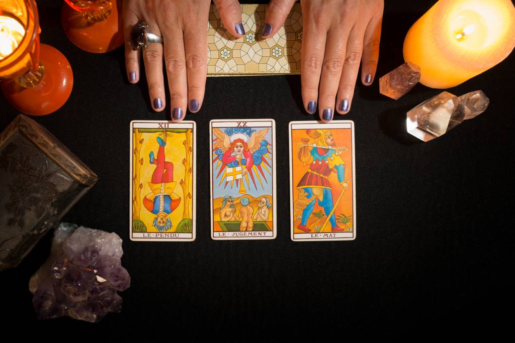 Detail of a hand showing three tarot cards. Detail of a hand showing three tarot cards.