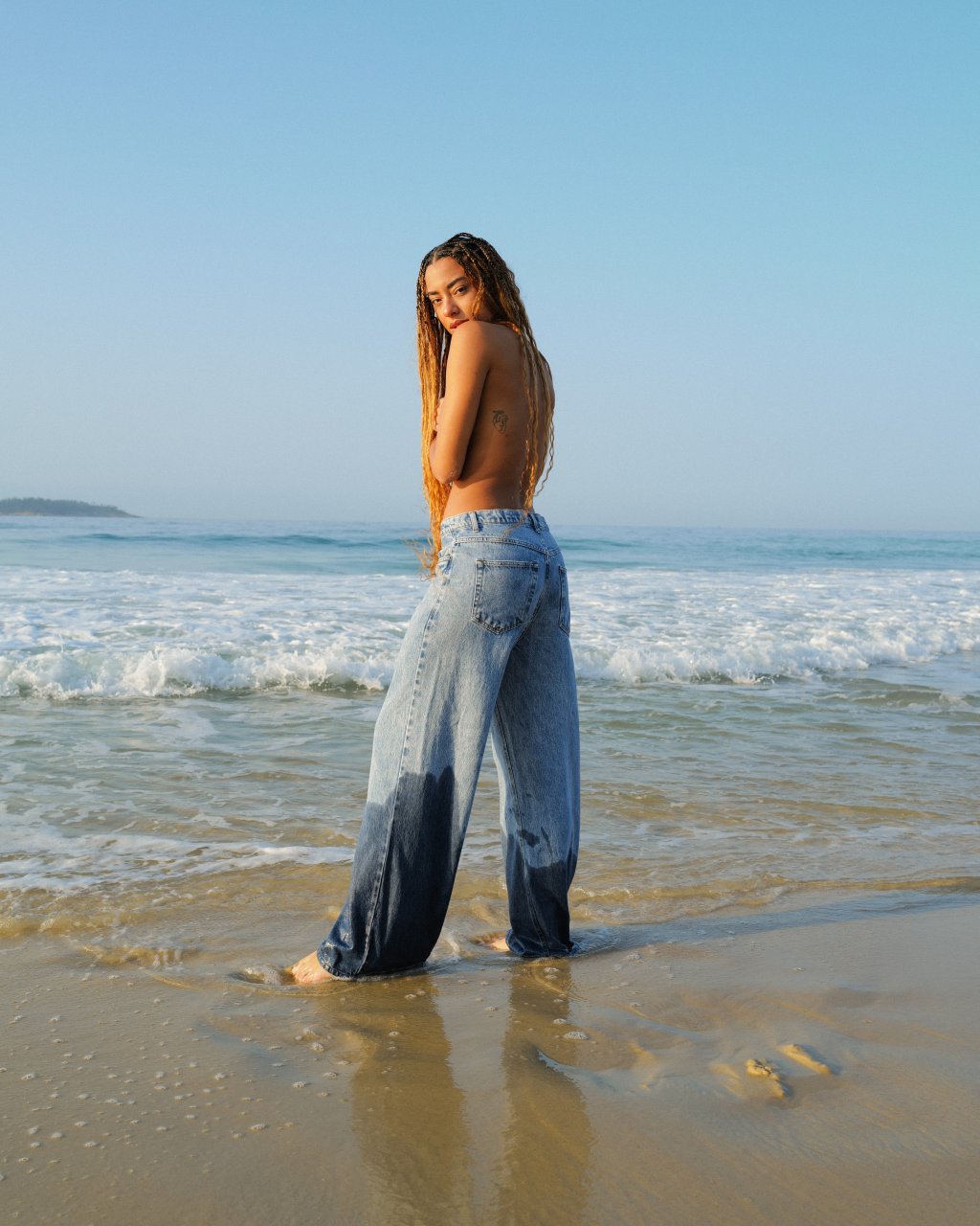 Yara Charry na praia com calça jeans