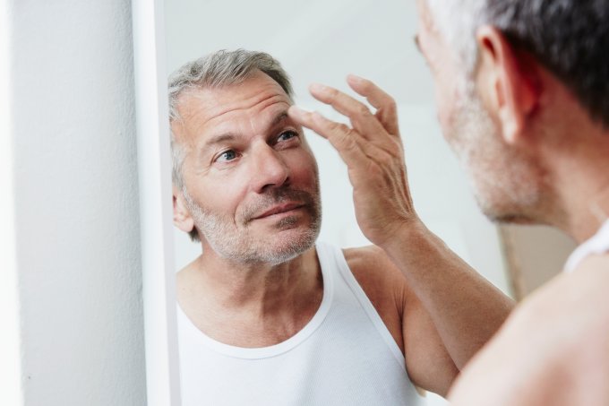 handsome middle-age man looking at his reflection in the mirror