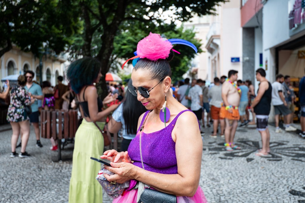 Mulher vestida para o Carnaval utilizando o seu celular
