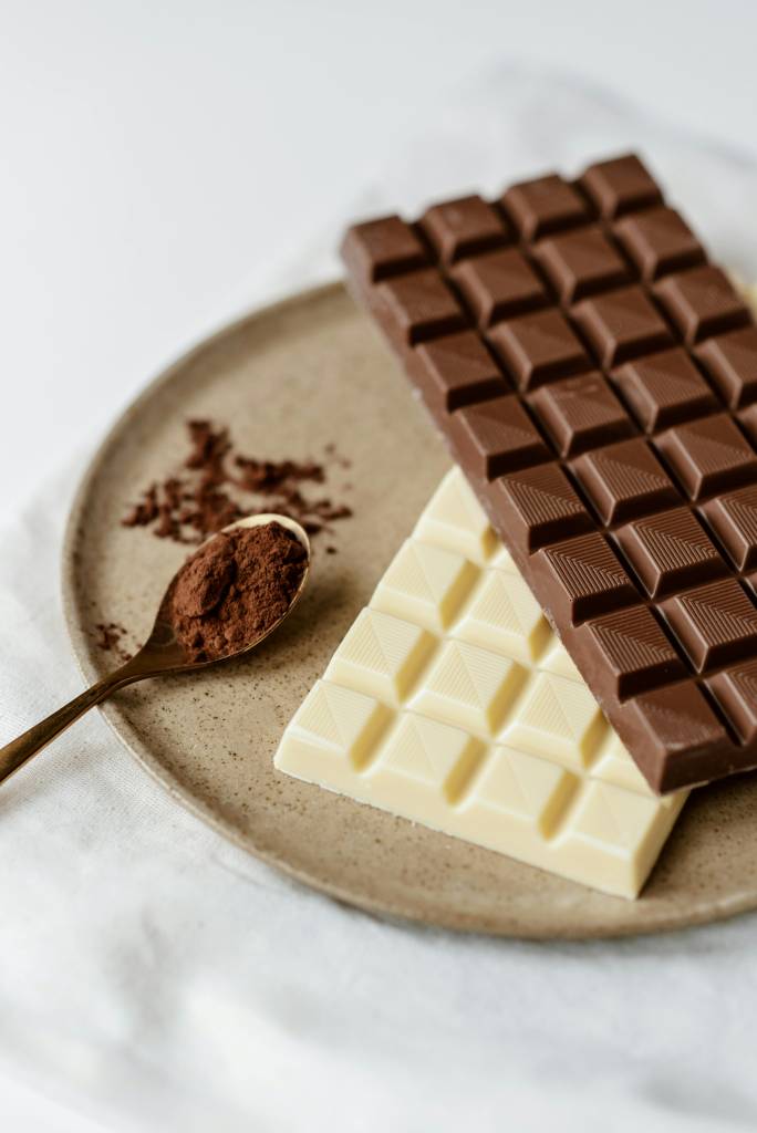 Chocolate-com-sabor-diferentes-entenda-os-diferentes-tipos-de-chocolate-o-que-muda Barras de chocolate e uma colher com chocolate em pó