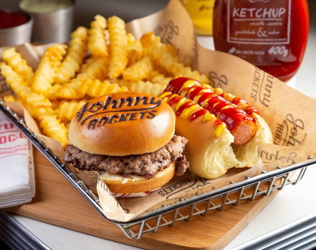 Entre as opções de menu kids de três lojas da rede Johnny Rockets está o combo com mini hotdog e um mini hambúrguer com mostarda, ketchup e maionese no pão brioche., fritas e bebida (suco ou refrigerante)