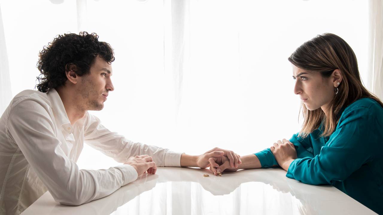Homem e mulher com problemas no relacionamento, se olhando, sérios, de mãos dadas. Problemas no relacionamento: como identificar se você é o culpado