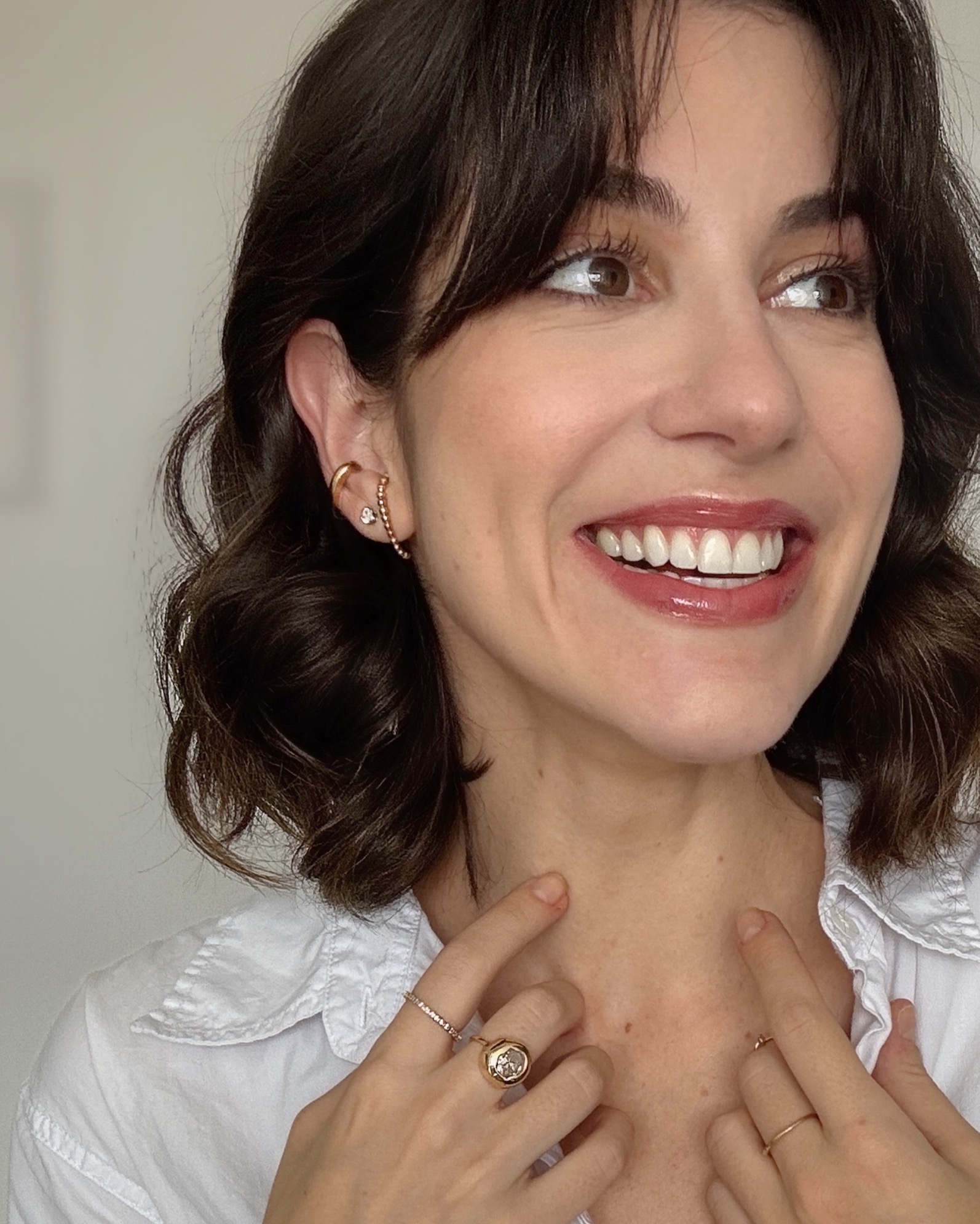 Lola Fanucchi veste camiseta branca enquanto posa sorrindo.
