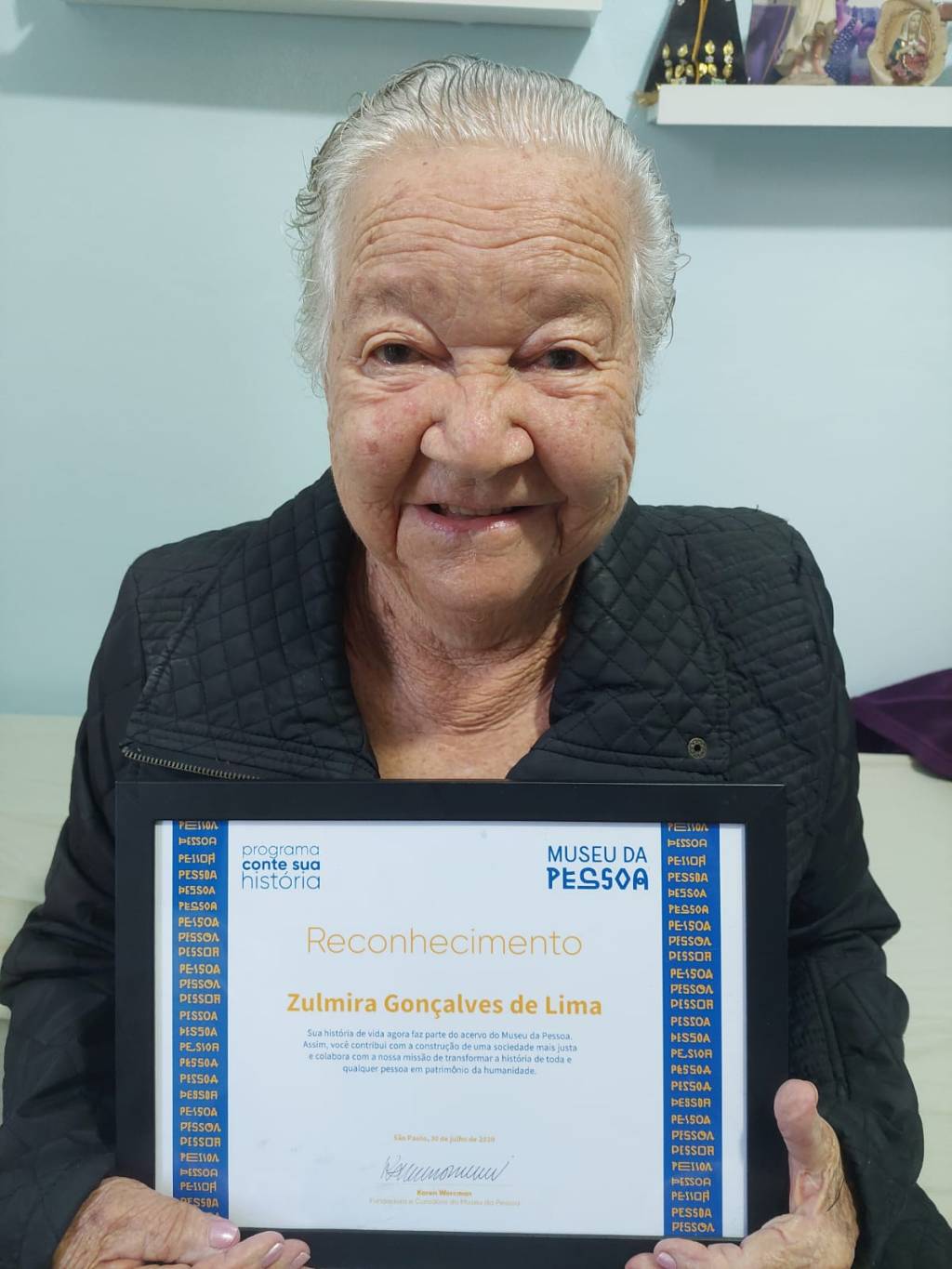 Museu da Pessoa – 250404 – Zulmira e seu certificado de depoente no Museu da Pessoa (Crédito Arquivo Pessoal) Foto de idosa segurando um certificado a sua frente