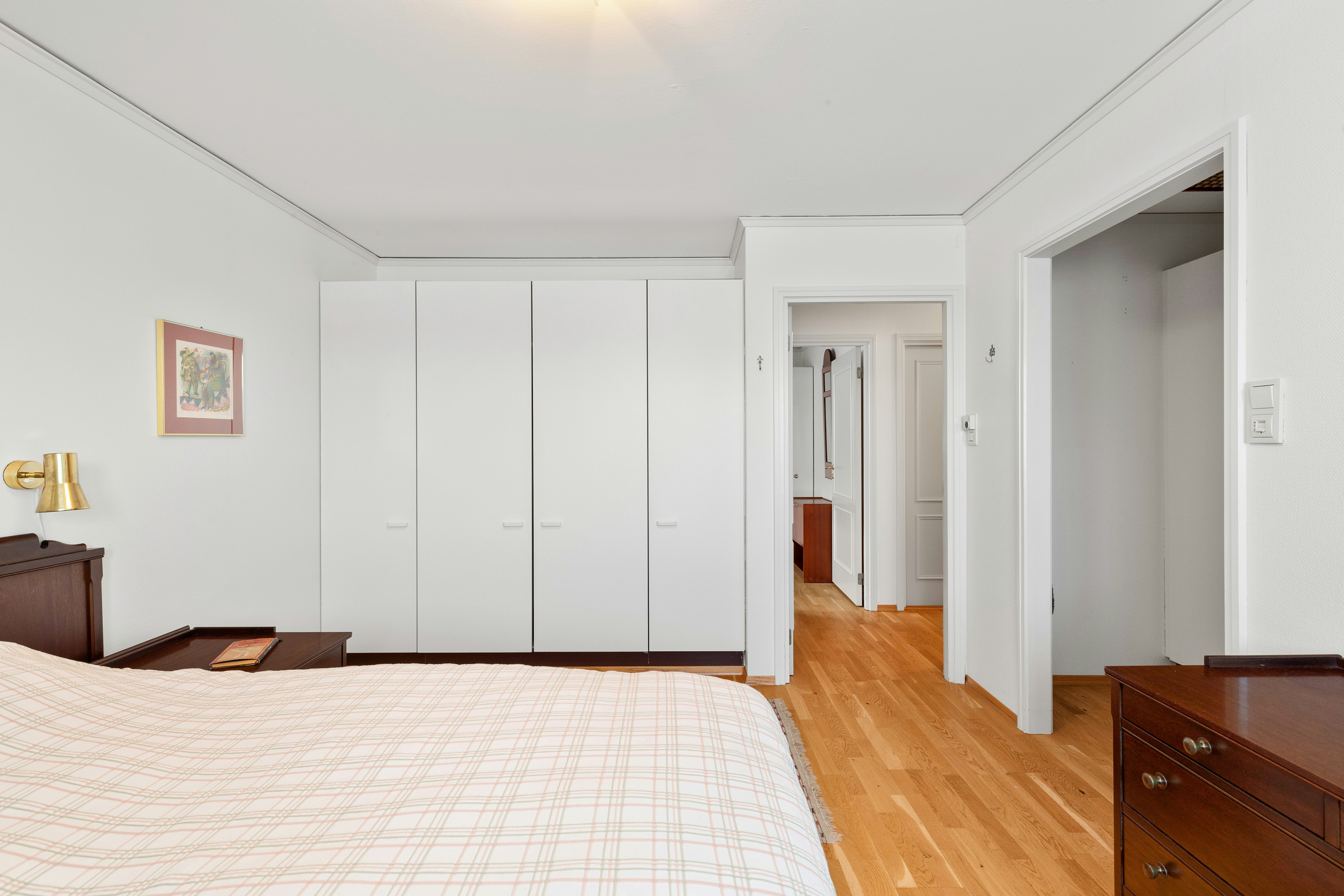 Guarda-roupa branco grande em quarto em tons claros.