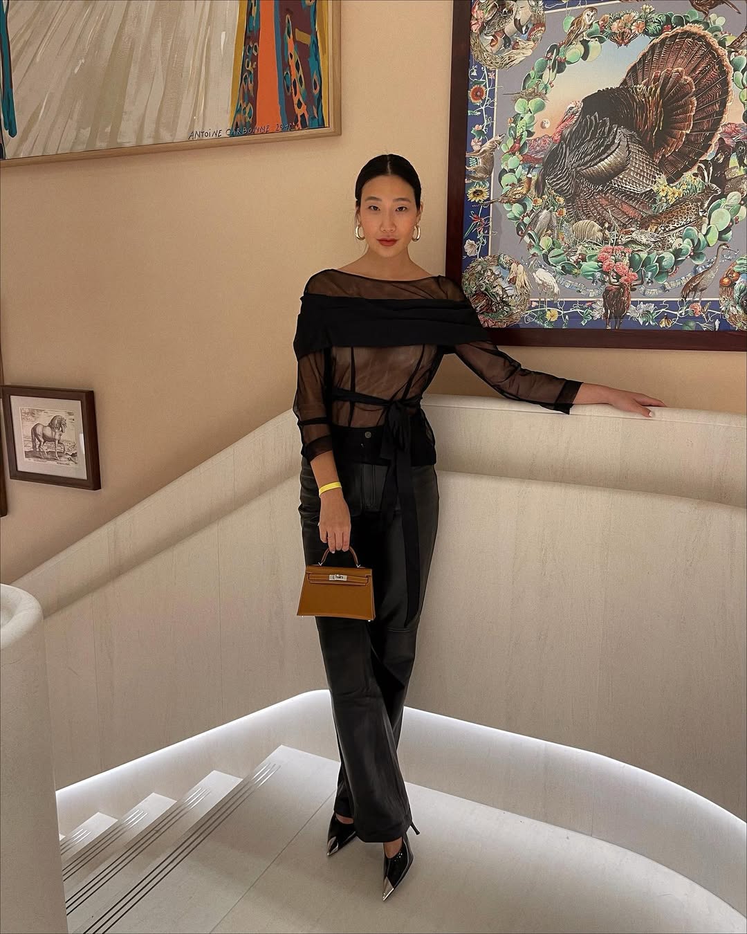 Look com calça preta, blusa transparente, bolsa bege e scarpin preto