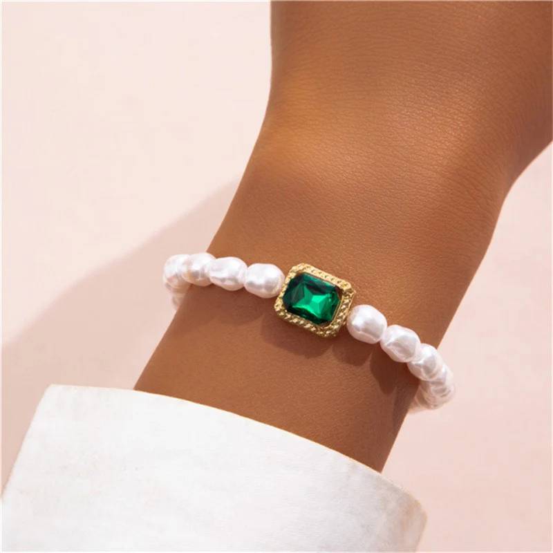 Imagem de braço com uma pulseira branca com detalhe em verde e dourado