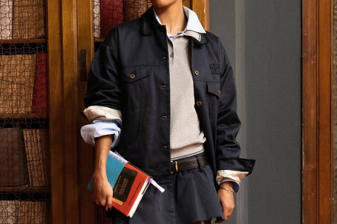mulher usando camisa polo e saia curta com jaqueta jeans