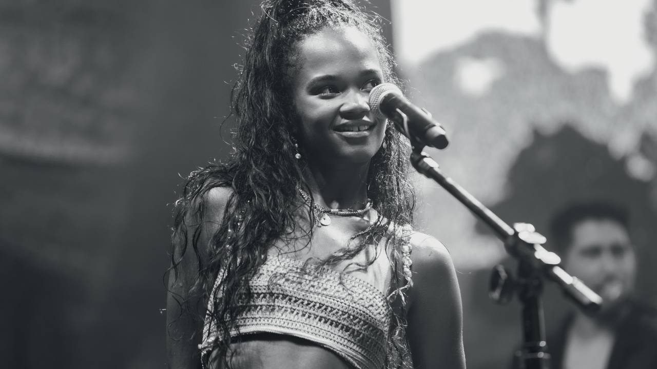 Imagem de mulher vista lateralmente cantando em um microfone