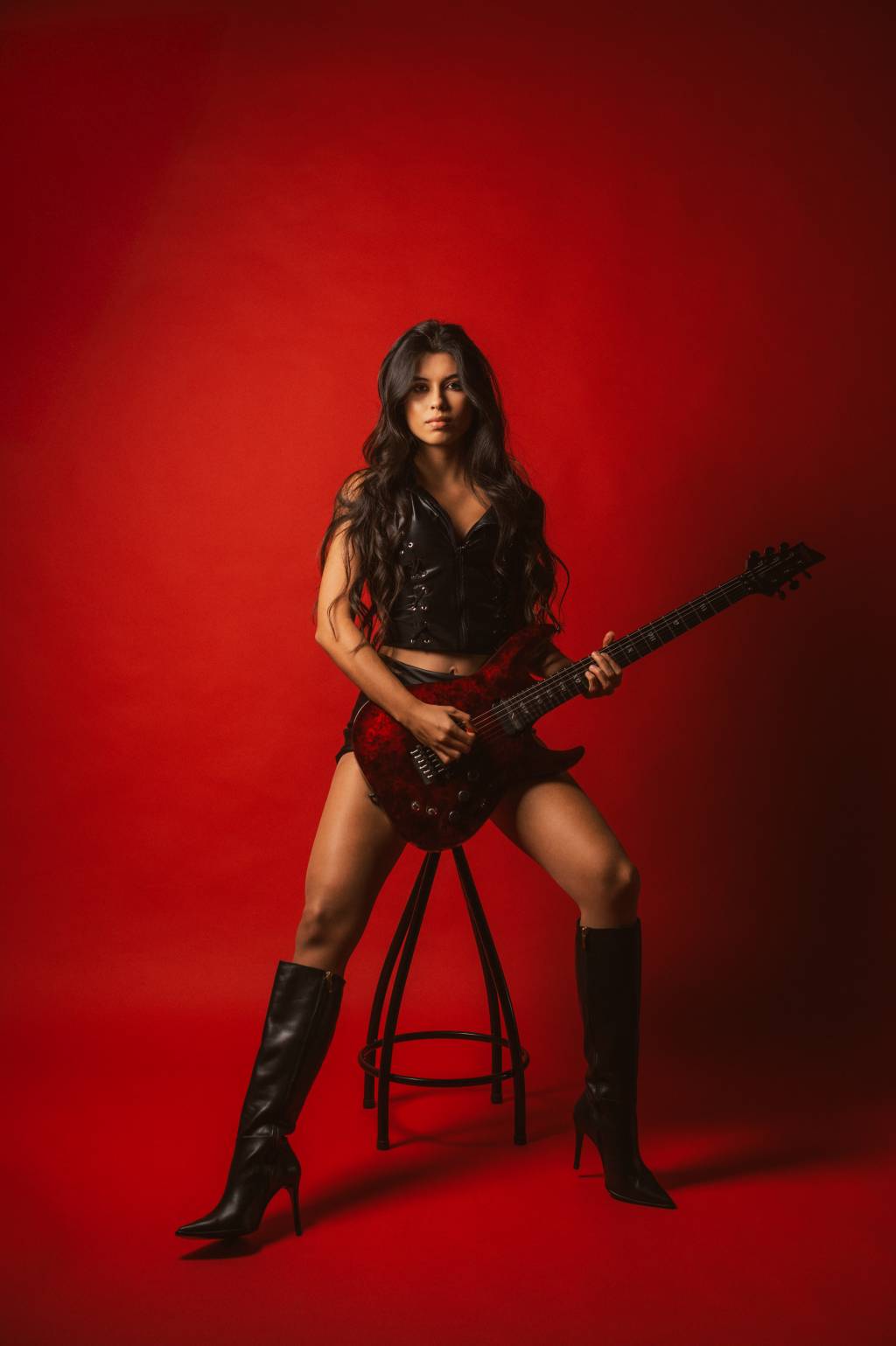 Larissa-Liveir-3_Cred_ Julia Missagia Imagem de mulher sentada em um banco segurando uma guitarra